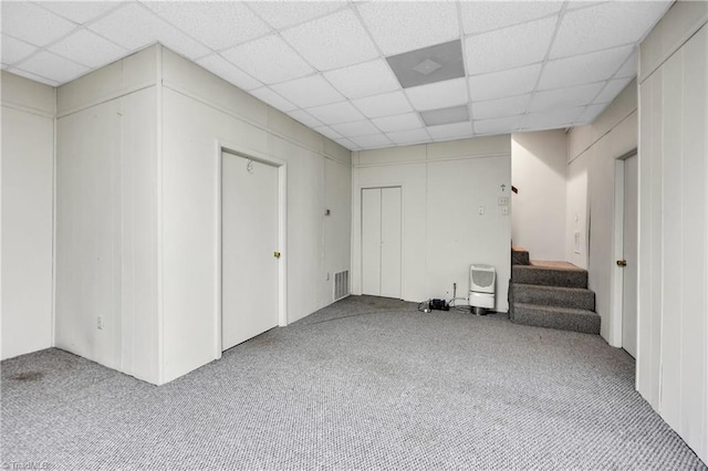 finished basement with carpet floors, visible vents, stairway, and a paneled ceiling