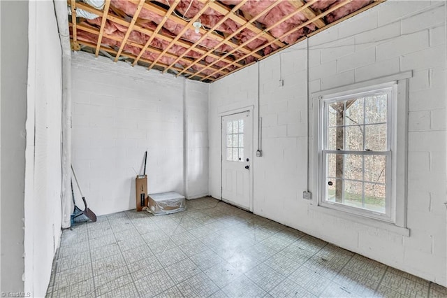 basement with a healthy amount of sunlight, concrete block wall, and tile patterned floors