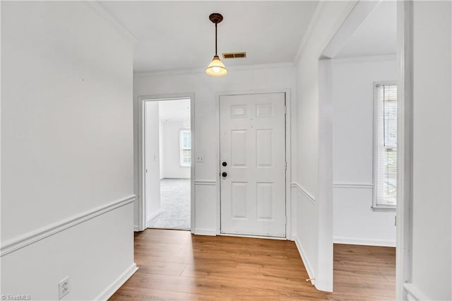 entrance foyer featuring light wood-style floors, visible vents, crown molding, and baseboards