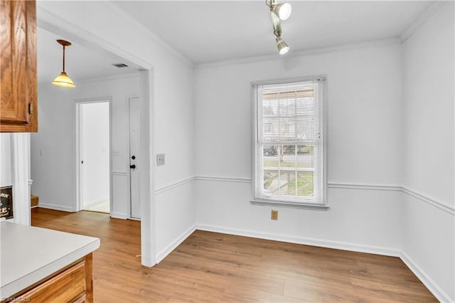 dining area featuring ornamental molding, light wood-style flooring, and baseboards