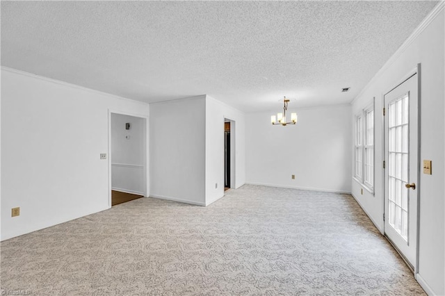 carpeted spare room featuring a chandelier, a textured ceiling, visible vents, and crown molding