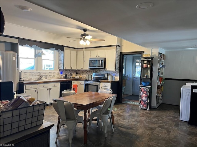 kitchen with white cabinetry, sink, ceiling fan, stainless steel appliances, and washer / clothes dryer