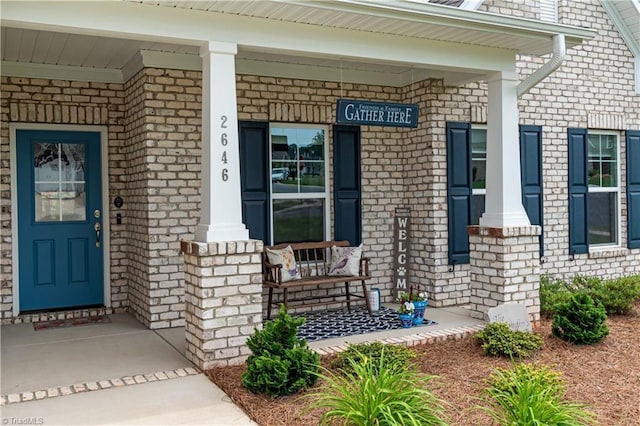 property entrance with a porch and brick siding