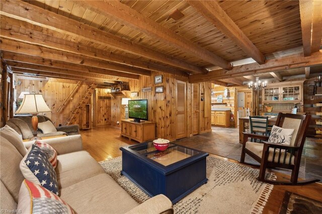 living room featuring wooden ceiling, beamed ceiling, wood walls, and an inviting chandelier