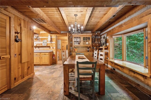 dining area featuring wood ceiling, beamed ceiling, an inviting chandelier, and wood walls