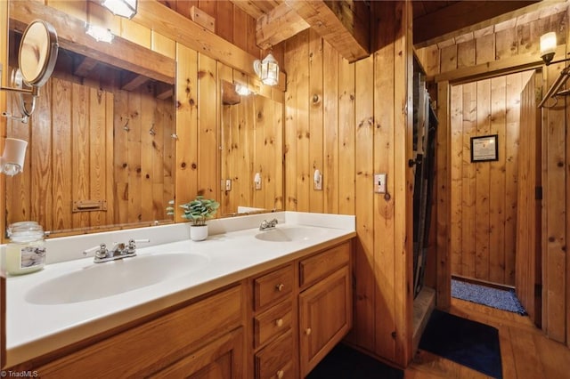 bathroom with wood-type flooring, wood walls, and dual bowl vanity