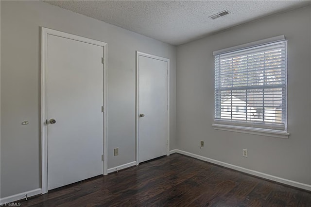 unfurnished bedroom featuring a textured ceiling and dark hardwood / wood-style flooring