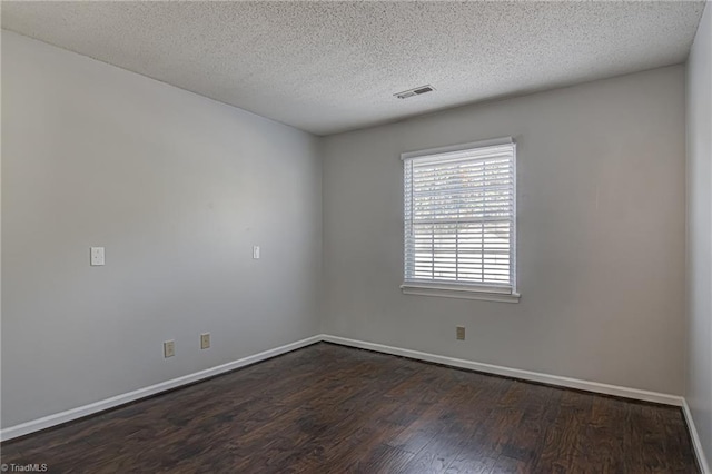 spare room featuring dark wood-type flooring and a textured ceiling