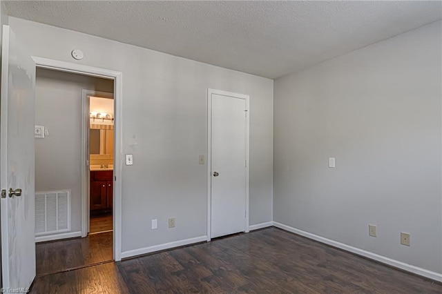 unfurnished bedroom with dark hardwood / wood-style flooring and a textured ceiling