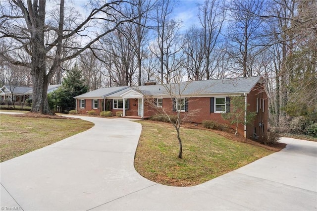 ranch-style house featuring driveway, brick siding, and a front lawn