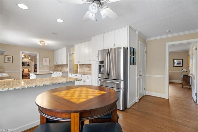 kitchen featuring light stone counters, tasteful backsplash, white cabinetry, wood finished floors, and stainless steel fridge with ice dispenser