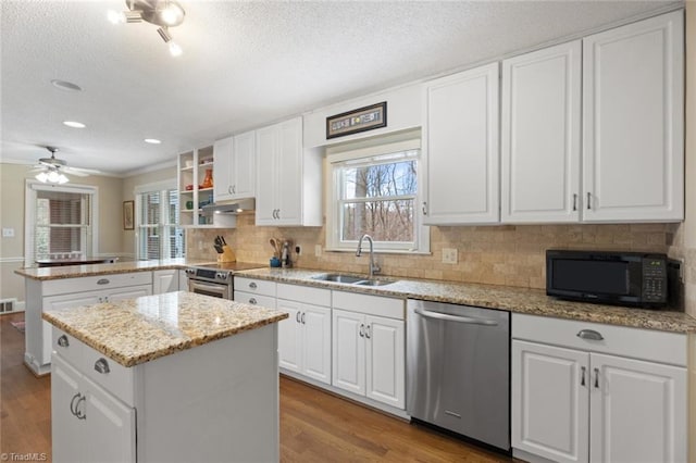 kitchen with appliances with stainless steel finishes, wood finished floors, a peninsula, under cabinet range hood, and a sink