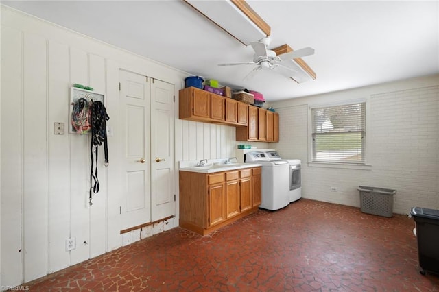 interior space with brick wall, a sink, a ceiling fan, independent washer and dryer, and cabinet space