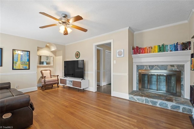 living room featuring ornamental molding, a fireplace, baseboards, and wood finished floors