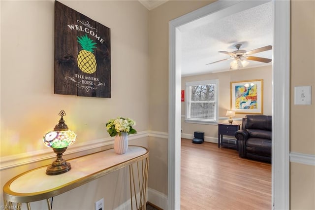 hall with a textured ceiling, wood finished floors, and baseboards