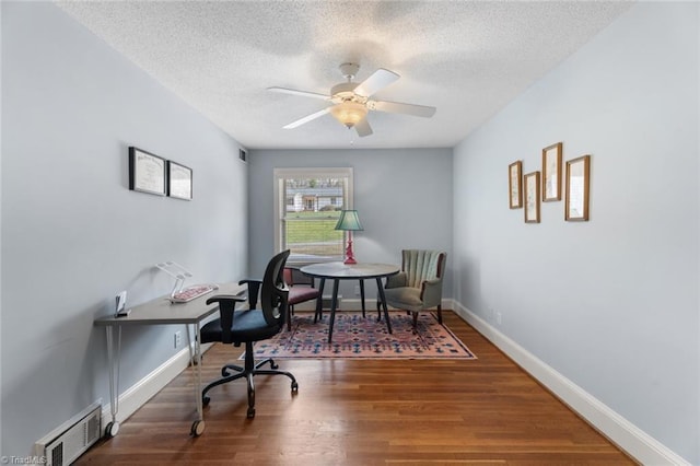 office space with baseboards, visible vents, a ceiling fan, wood finished floors, and a textured ceiling