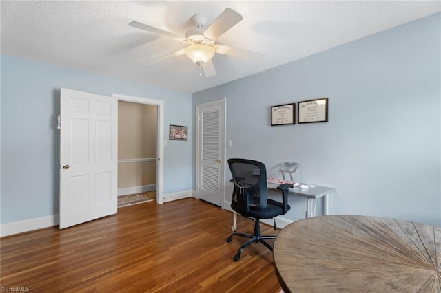 home office with a ceiling fan, a textured ceiling, baseboards, and wood finished floors