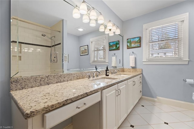 full bathroom featuring double vanity, baseboards, a tile shower, and a sink