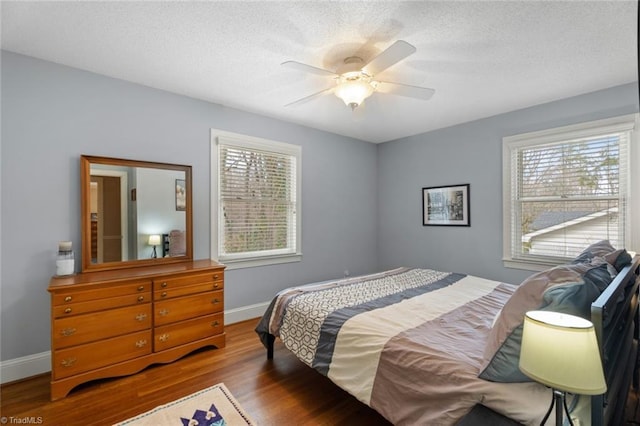 bedroom featuring a textured ceiling, baseboards, and wood finished floors