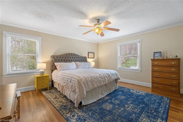 bedroom with baseboards, a textured ceiling, ornamental molding, and wood finished floors