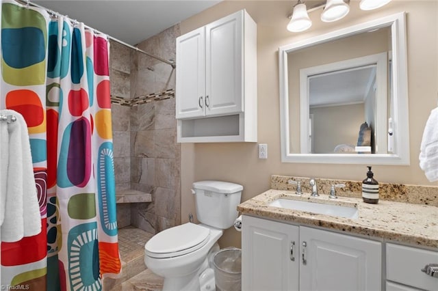 bathroom featuring toilet, tiled shower, and vanity