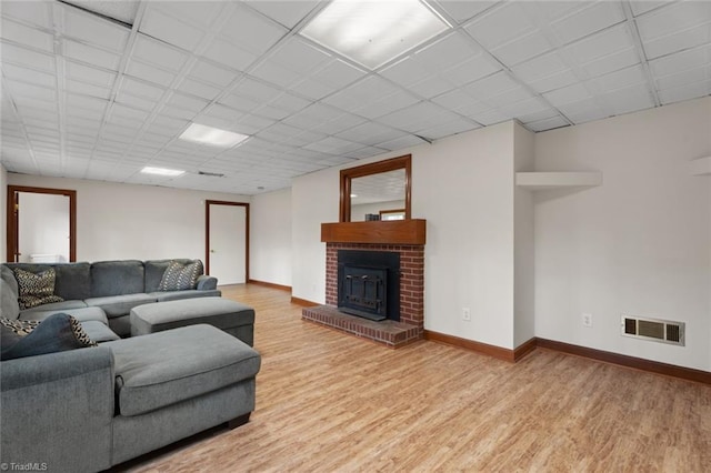 living area with visible vents, a fireplace, baseboards, and wood finished floors