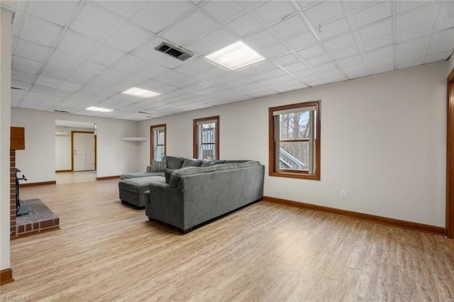 living area with light wood-type flooring, visible vents, and baseboards