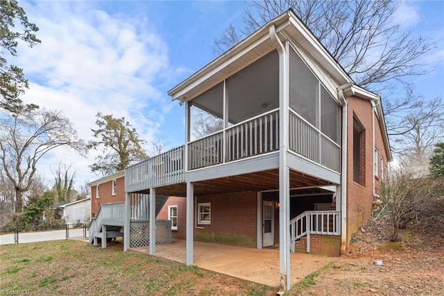 view of front of property with a patio, brick siding, a sunroom, stairway, and a carport