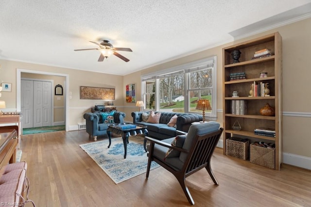 living area featuring ornamental molding, a ceiling fan, a textured ceiling, and wood finished floors