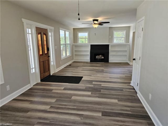 unfurnished living room featuring dark hardwood / wood-style flooring and ceiling fan