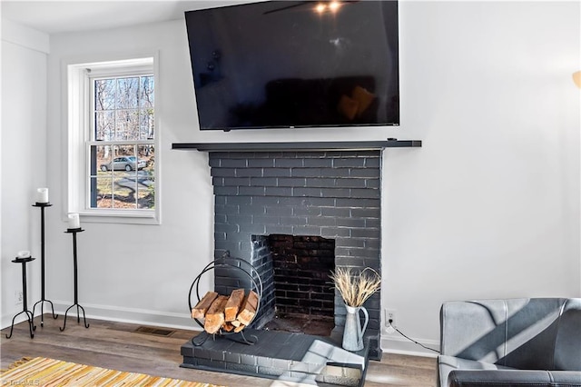 interior details with baseboards, a brick fireplace, and wood finished floors