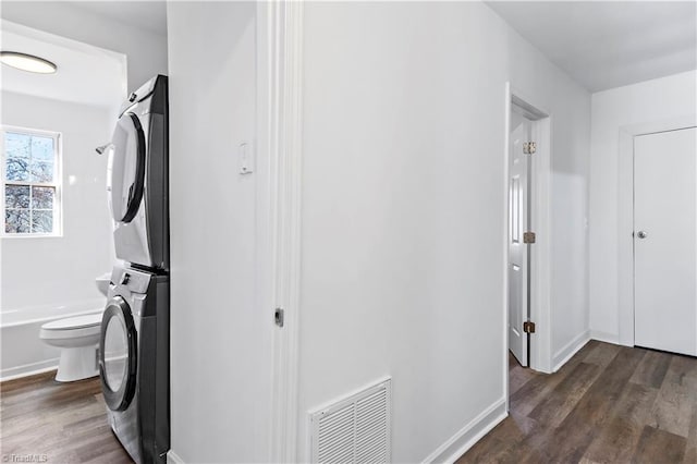 washroom featuring visible vents, dark wood finished floors, laundry area, and stacked washing maching and dryer