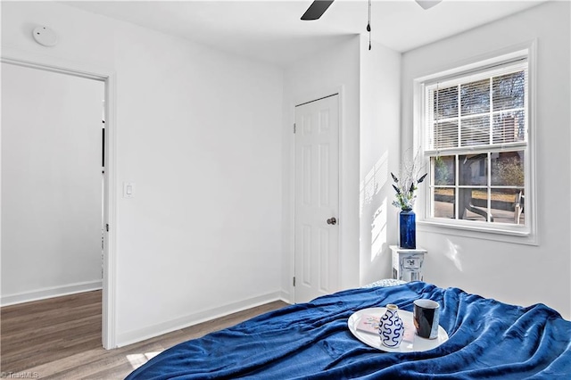 bedroom featuring a ceiling fan, baseboards, and wood finished floors