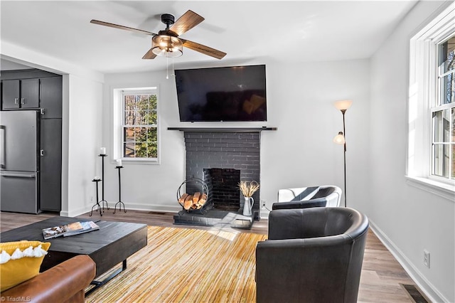 living area featuring visible vents, ceiling fan, baseboards, light wood-type flooring, and a fireplace