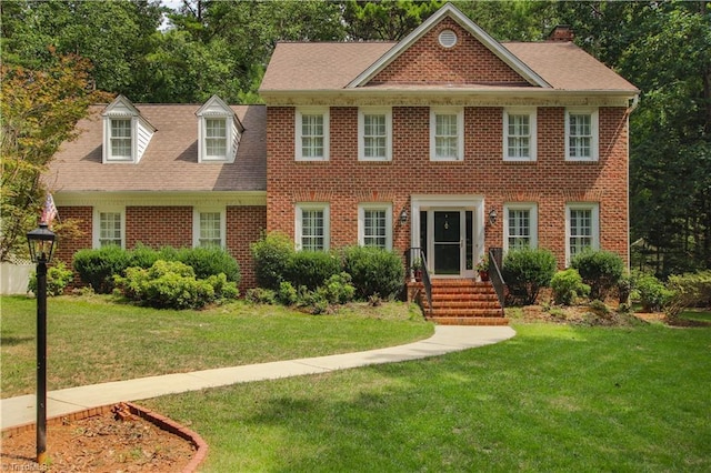 colonial inspired home featuring a front yard and brick siding