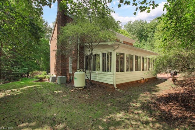 view of side of home featuring a sunroom, a lawn, and central air condition unit