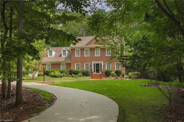 colonial inspired home featuring a front yard, concrete driveway, and brick siding