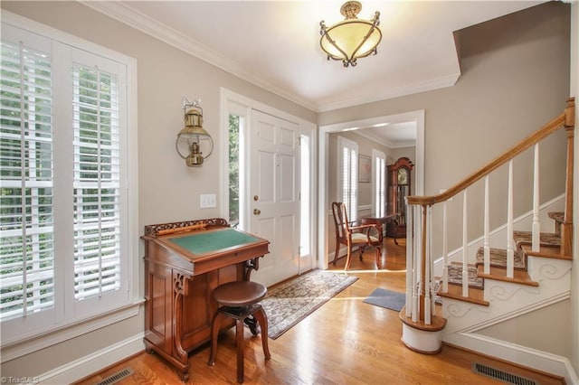 entrance foyer with baseboards, visible vents, stairway, ornamental molding, and wood finished floors