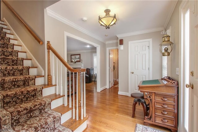 foyer entrance featuring stairs, light wood finished floors, baseboards, and crown molding