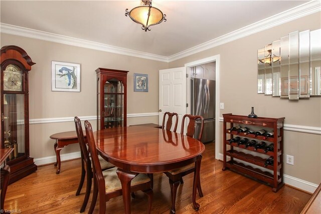 dining space with baseboards, wood finished floors, and crown molding