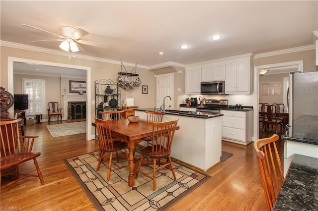 dining space with light wood-style floors, a brick fireplace, and ornamental molding