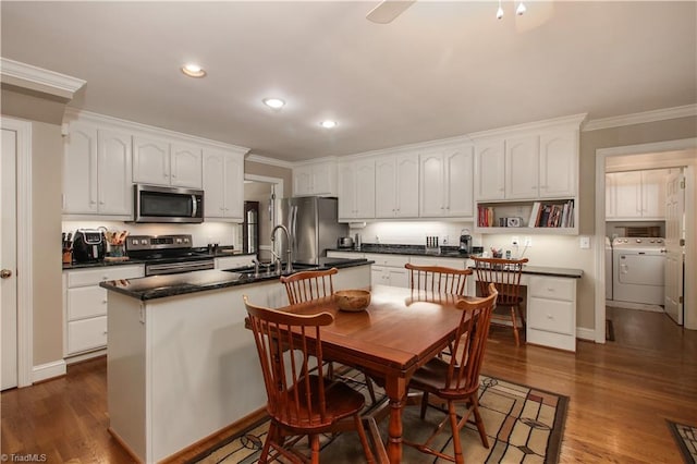 kitchen with a kitchen island with sink, appliances with stainless steel finishes, dark hardwood / wood-style flooring, and sink