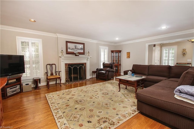 living room featuring crown molding, wood-type flooring, and a brick fireplace