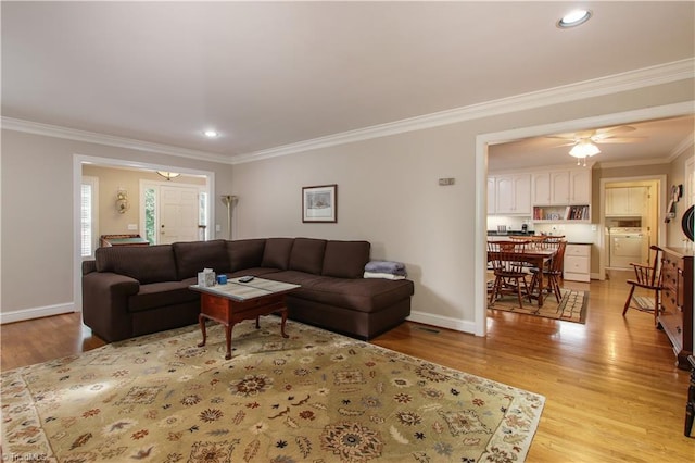 living room with washer / clothes dryer, ceiling fan, light hardwood / wood-style floors, and ornamental molding