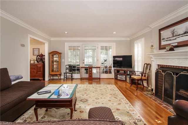 living room featuring ornamental molding, wood-type flooring, a brick fireplace, and a wealth of natural light