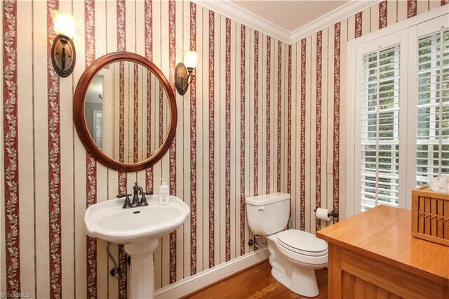 bathroom with a healthy amount of sunlight, toilet, ornamental molding, and wood-type flooring