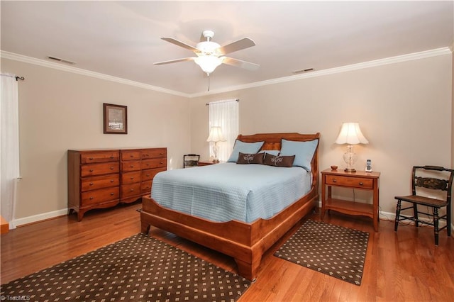 bedroom with crown molding, visible vents, and wood finished floors