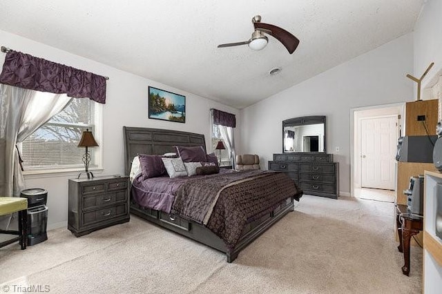 bedroom with ceiling fan, vaulted ceiling, light colored carpet, and a textured ceiling