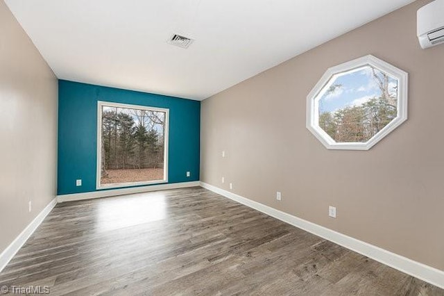 spare room with a wealth of natural light, wood-type flooring, and a wall mounted air conditioner