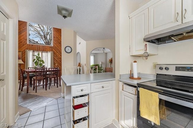 kitchen with wood walls, white cabinets, kitchen peninsula, a textured ceiling, and electric stove